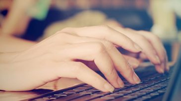 Female hands typing on laptop with retro filter effect